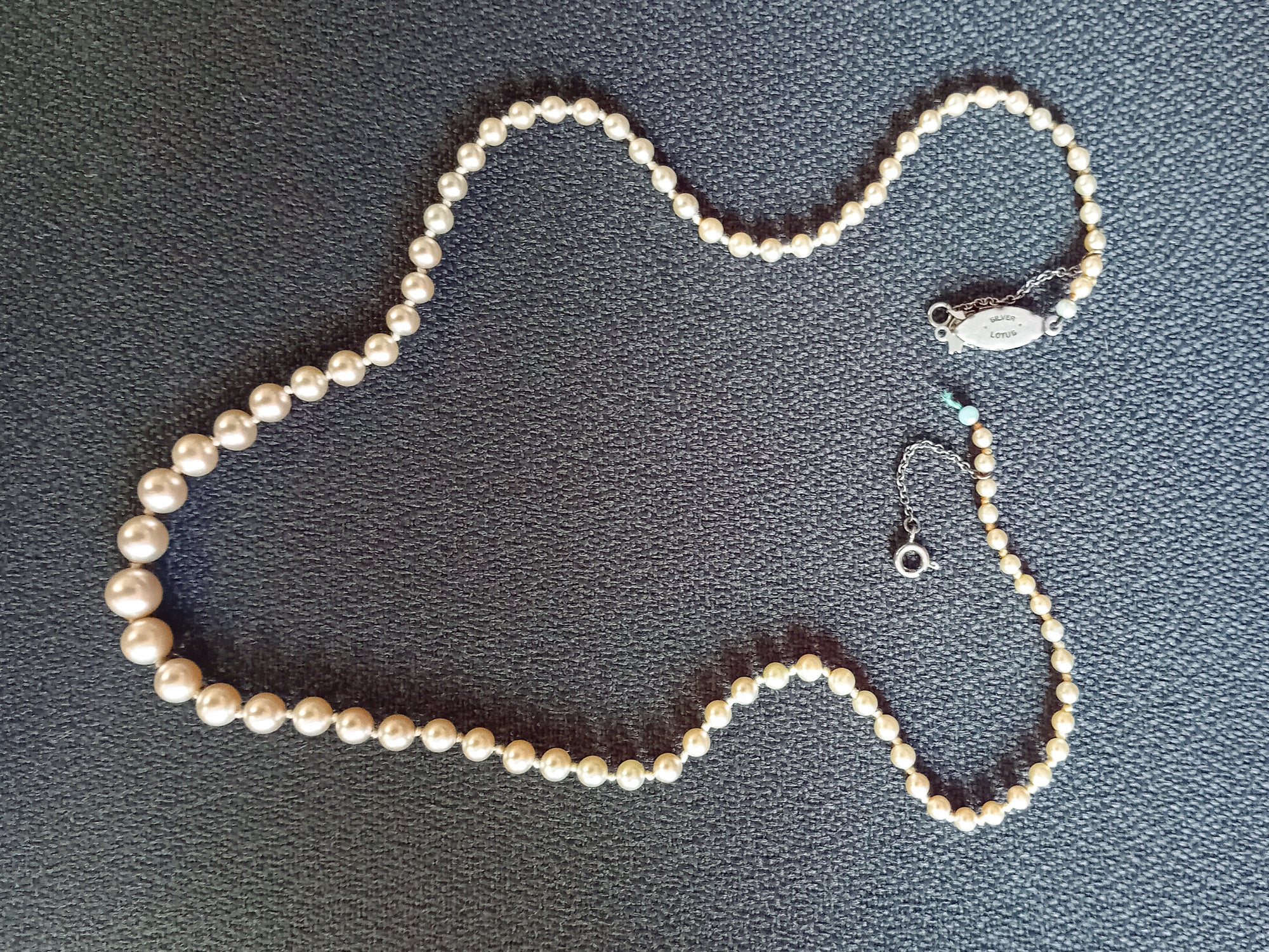 Broken graduated pearl necklace with detached clasp before restringing repair